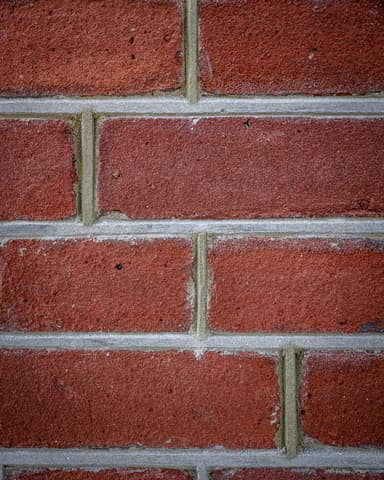 Medewerker strijkt voegwerk na op rode bakstenen gevel bij conserveren metselwerk Hofsingel Vlaardingen