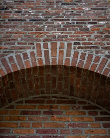 Medewerker hakt voegwerk uit op kerkgevel met pneumatisch gereedschap bij conserveren metselwerk Willemstad