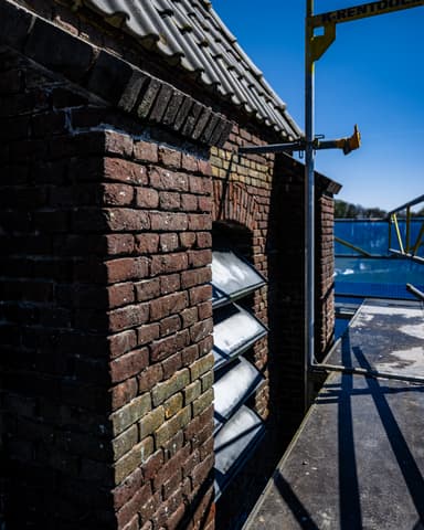 Kerktoren ingepakt in blauw steigergaas gezien vanuit dorp bij conserveren metselwerk Willemstad