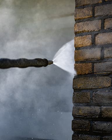 Medewerker op hoogwerker met stoomwolk bij gevelreiniging VvE-complex in Ridderkerk