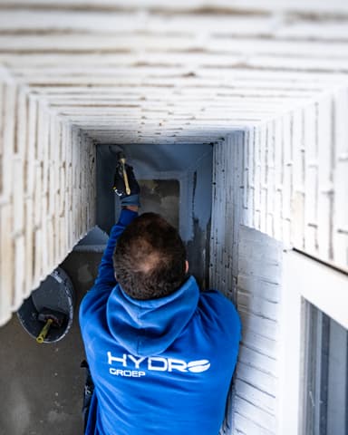 Specie op troffel tijdens voegwerkreparatie aan balkon in Rotterdam door Hydro Groep voor Verhoeven Bouwt