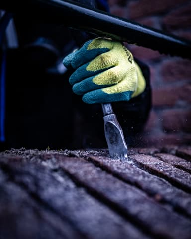 Vakman met gasmasker werkt aan uitgehakt voegwerk in Rhoon door Hydro Groep