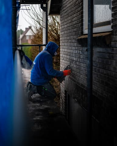 Voorgevel met Hydro Groep steiger en beschermdoek in Hellevoetsluis tijdens conserveren metselwerk