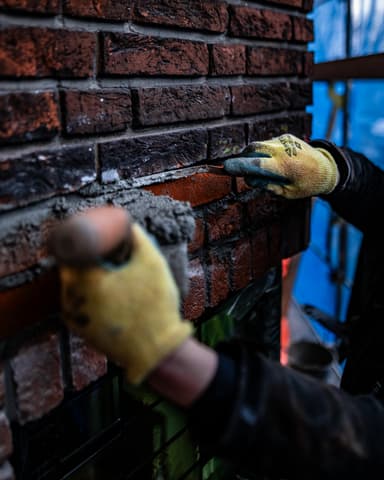 Vakman bereidt stenen voor op steiger bij gevel in Voorburg tijdens betonreparatie door Hydro Groep
