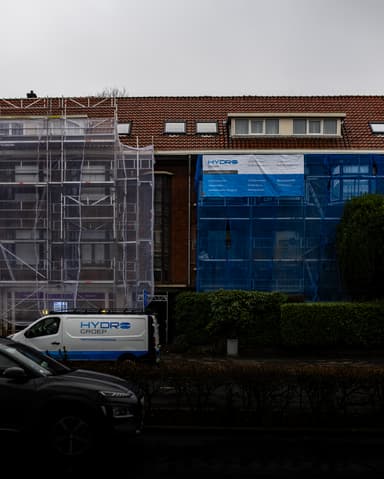 Vakman voegt metselwerk in op steiger in zwart-wit in Voorburg door Hydro Groep