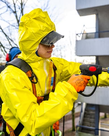 Vakman repareert voegwerk bij betonbalkon op hoogte in Rotterdam door Hydro Groep