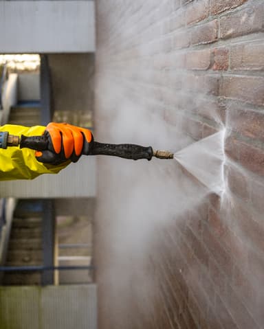 Vakman in hoogwerker brengt conservering aan op gevel in Rotterdam door Hydro Groep