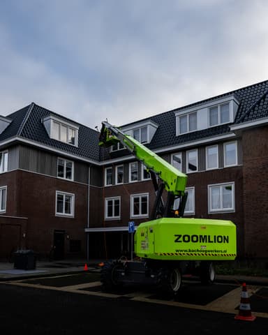 Hydro Groep medewerker lacht op dak bij reinigingswerk wooncomplex in Oostvoorne