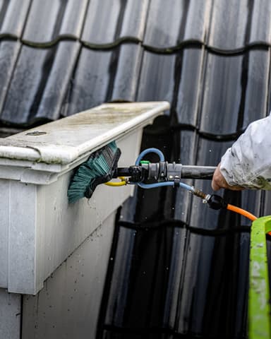 Portret vakman reinigt balkonrand op hoogte in zwart-wit in Oostvoorne door Hydro Groep