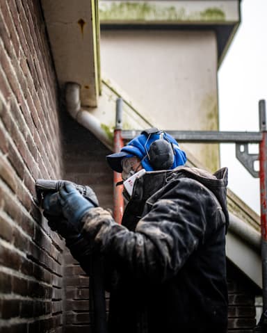 Vakman slijpt voegwerk uit op steiger met stofwolk in Hellevoetsluis door Hydro Groep