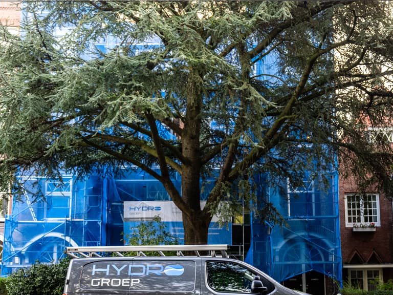 Hydro Groep bedrijfsbus voor steiger aan voorgevel tijdens betonreparatie in Rotterdam