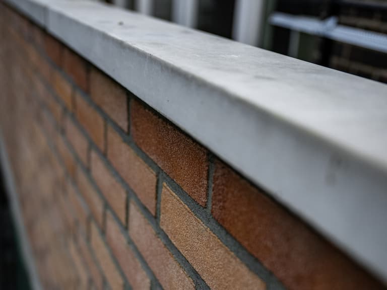 Vakman trekt halfsteens buitenmuur op met waterpas bij betonreparatie in Rotterdam door Hydro Groep