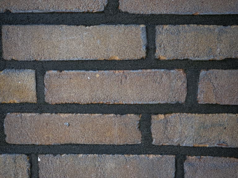 Medewerker repareert voegwerk bij raamkozijn op begane grond tijdens conserveren metselwerk Dordrecht