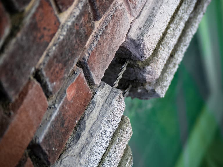 Voorgevel VvE met steiger en blauw gaas in tegenlicht bij betonreparatie in Den Haag